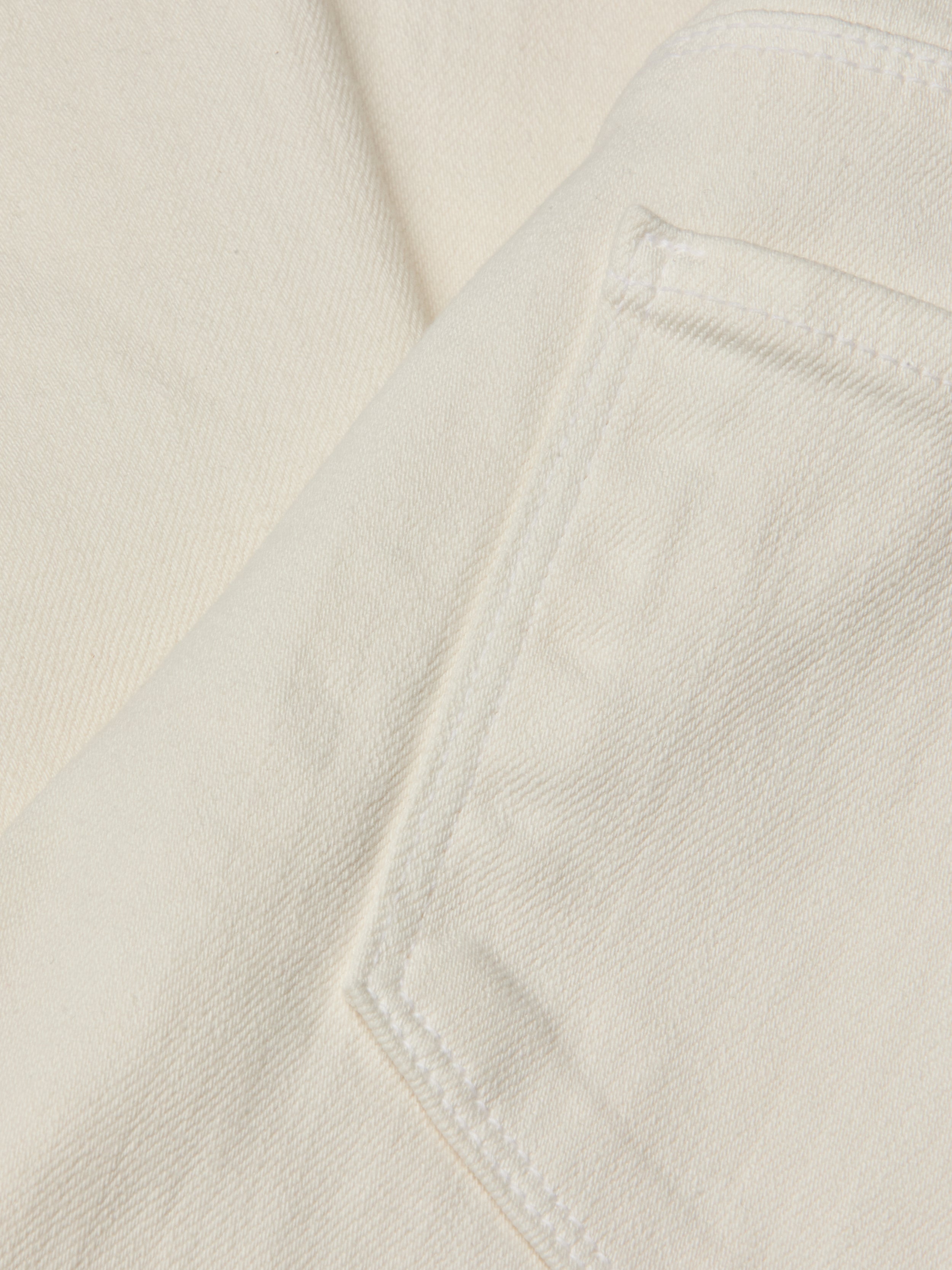Close-up of a cream-colored fabric with a visible pocket seam and diagonal twill texture, likely part of the Joanne Low-Rise Wide-Leg Jean in an ecru wash.
