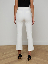 A woman is shown from the back against a plain light background, wearing the Ketra Bootcut Trouser in white stretch suit fabric, paired with black heels.