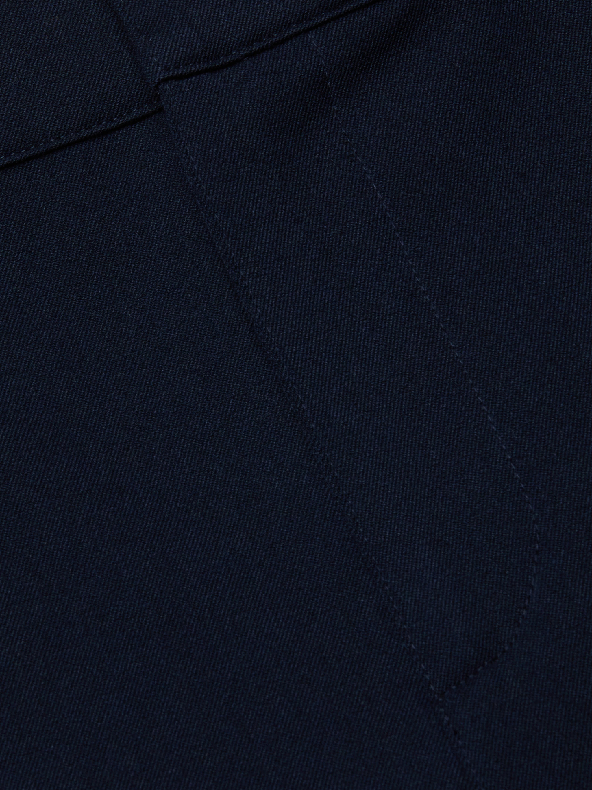 Close-up of midnight navy stretch fabric from the Ketra Bootcut Trouser, featuring visible stitching and seam lines. The material has a smooth yet slightly textured appearance.