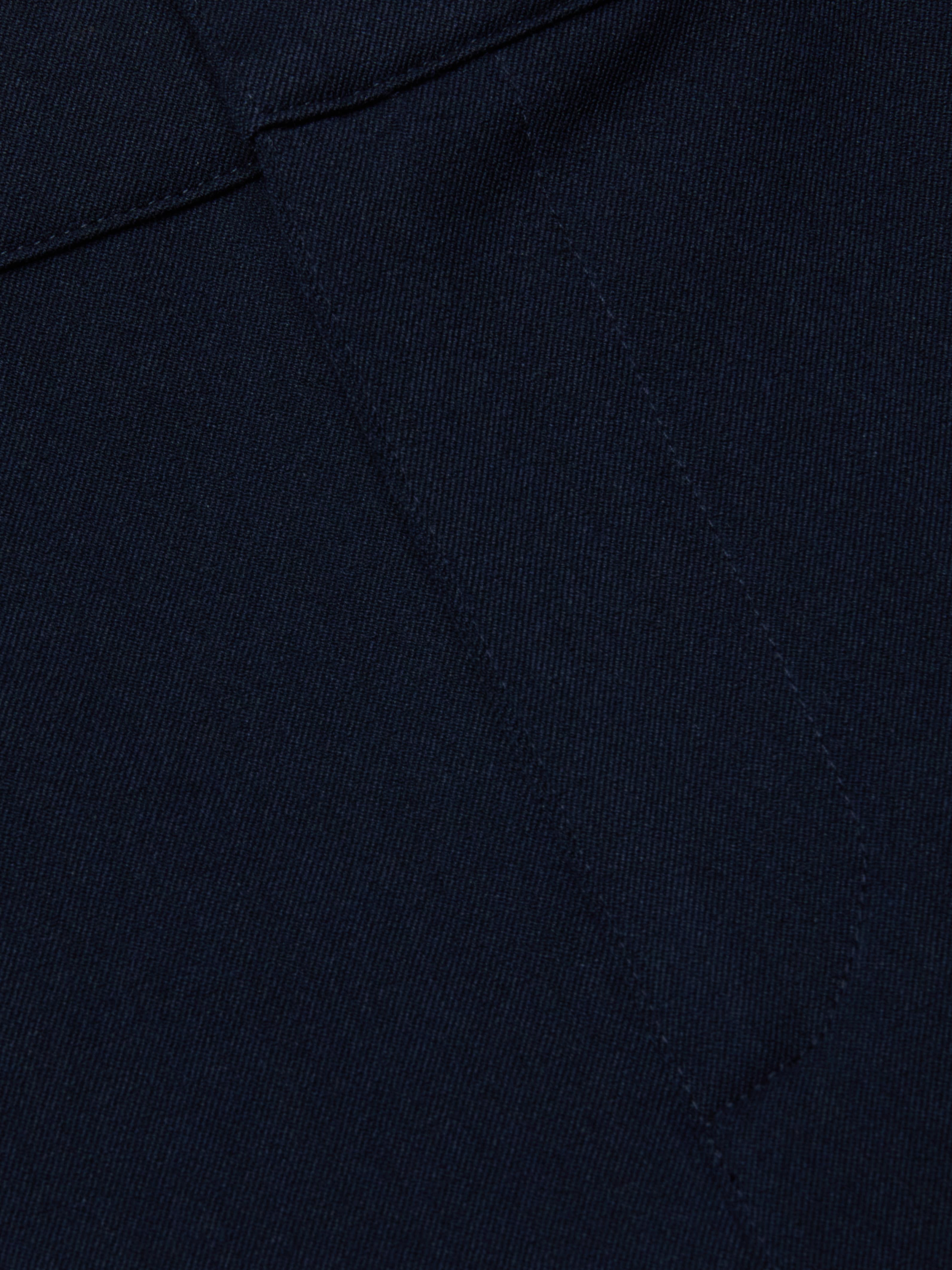 Close-up of midnight navy stretch fabric from the Ketra Bootcut Trouser, featuring visible stitching and seam lines. The material has a smooth yet slightly textured appearance.