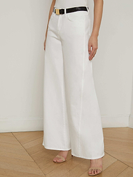 A person wearing the Beau Wide-Leg Jean in white, styled with a black belt and open-toe heels, stands against a plain, light background.