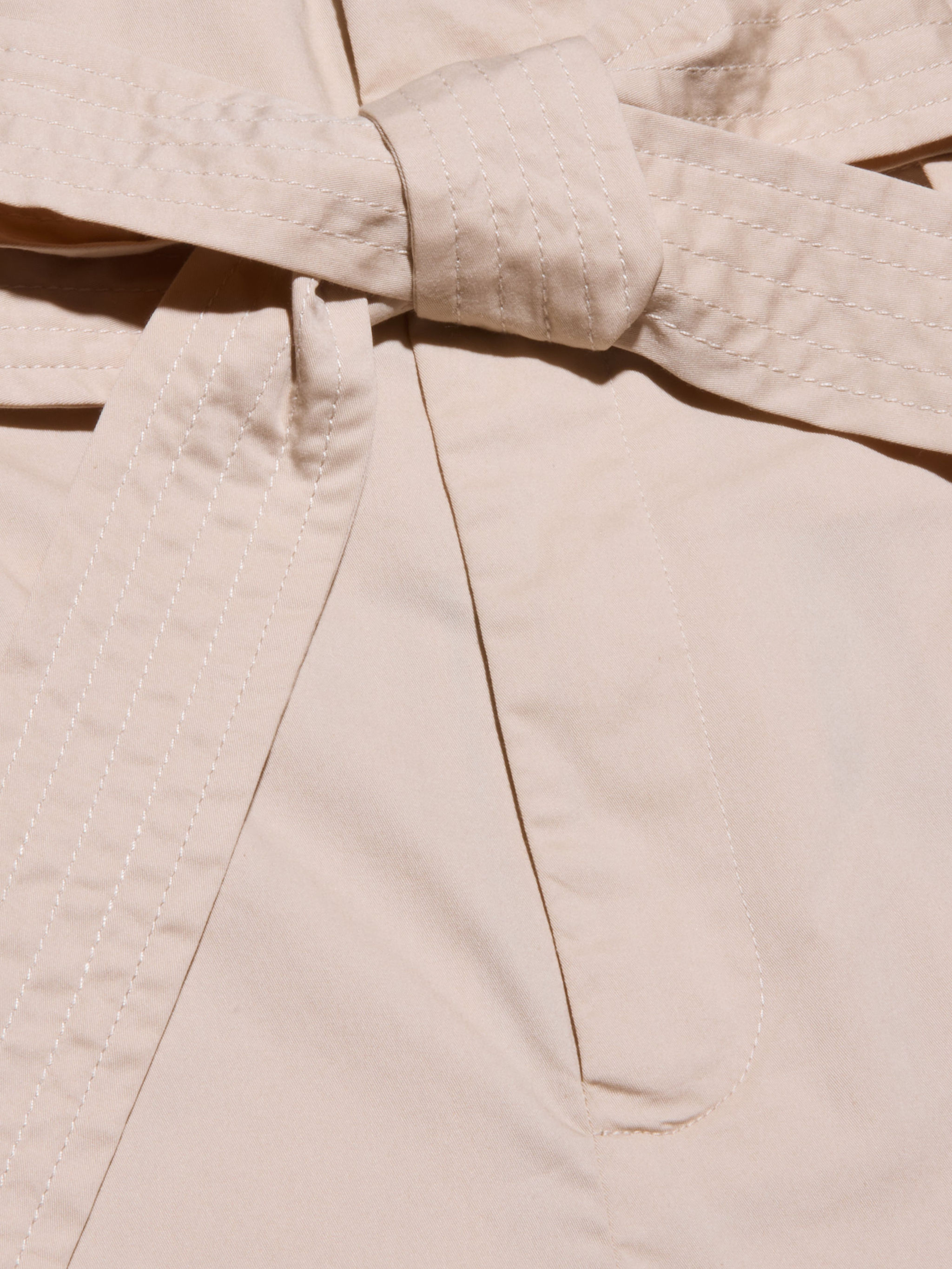 Close-up of a beige self-tie belt, part of the Damira Poplin Short, with visible stitching along the edges.