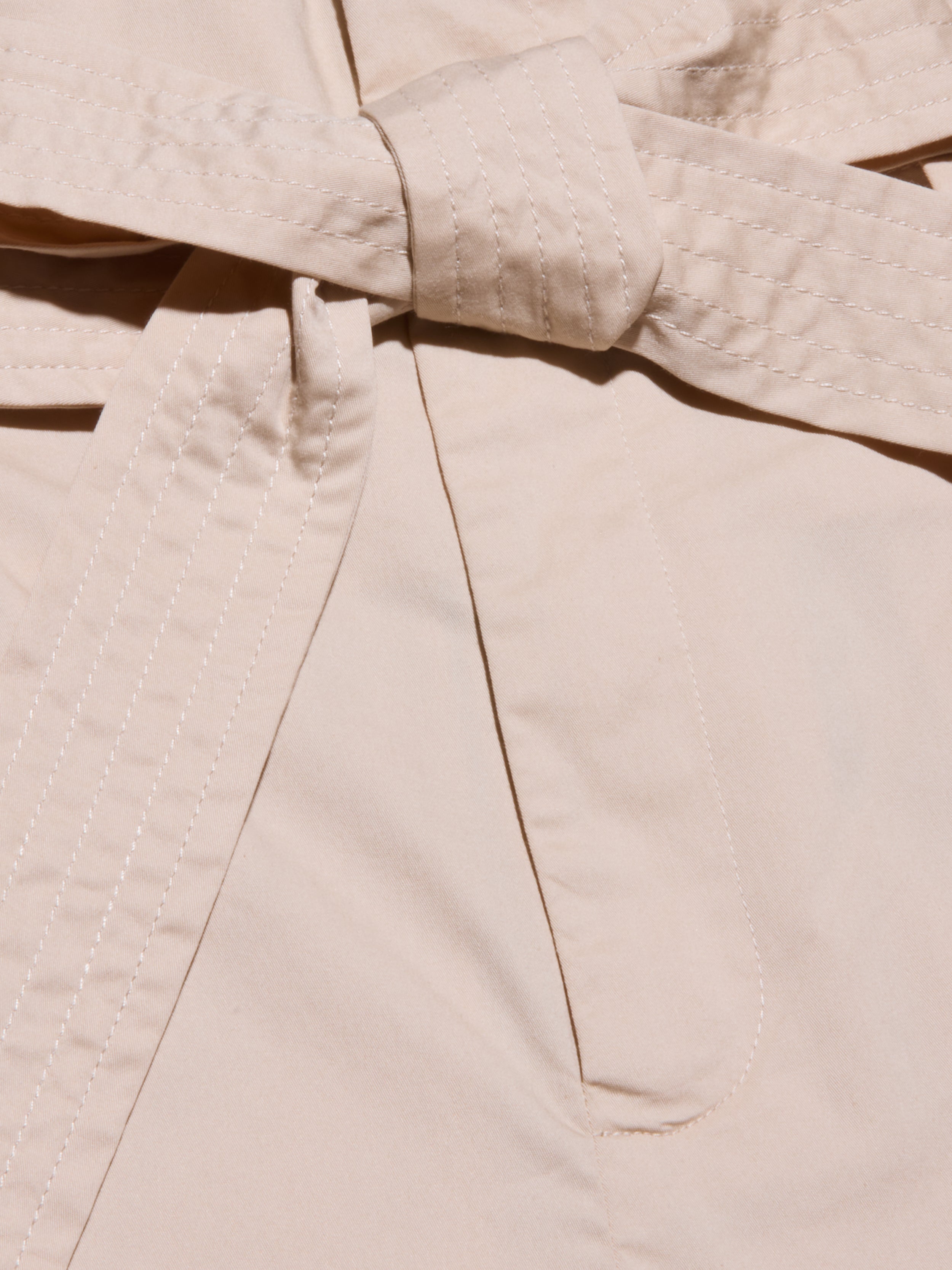 Close-up of a beige self-tie belt, part of the Damira Poplin Short, with visible stitching along the edges.
