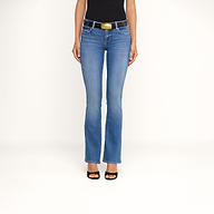 Indossando i jeans Cara a vita bassa e taglio bootcut, un top nero senza maniche, una cintura nera con una grande fibbia dorata e sandali neri con tacco, una persona è in piedi su uno sfondo beige. Il suo volto non è visibile.