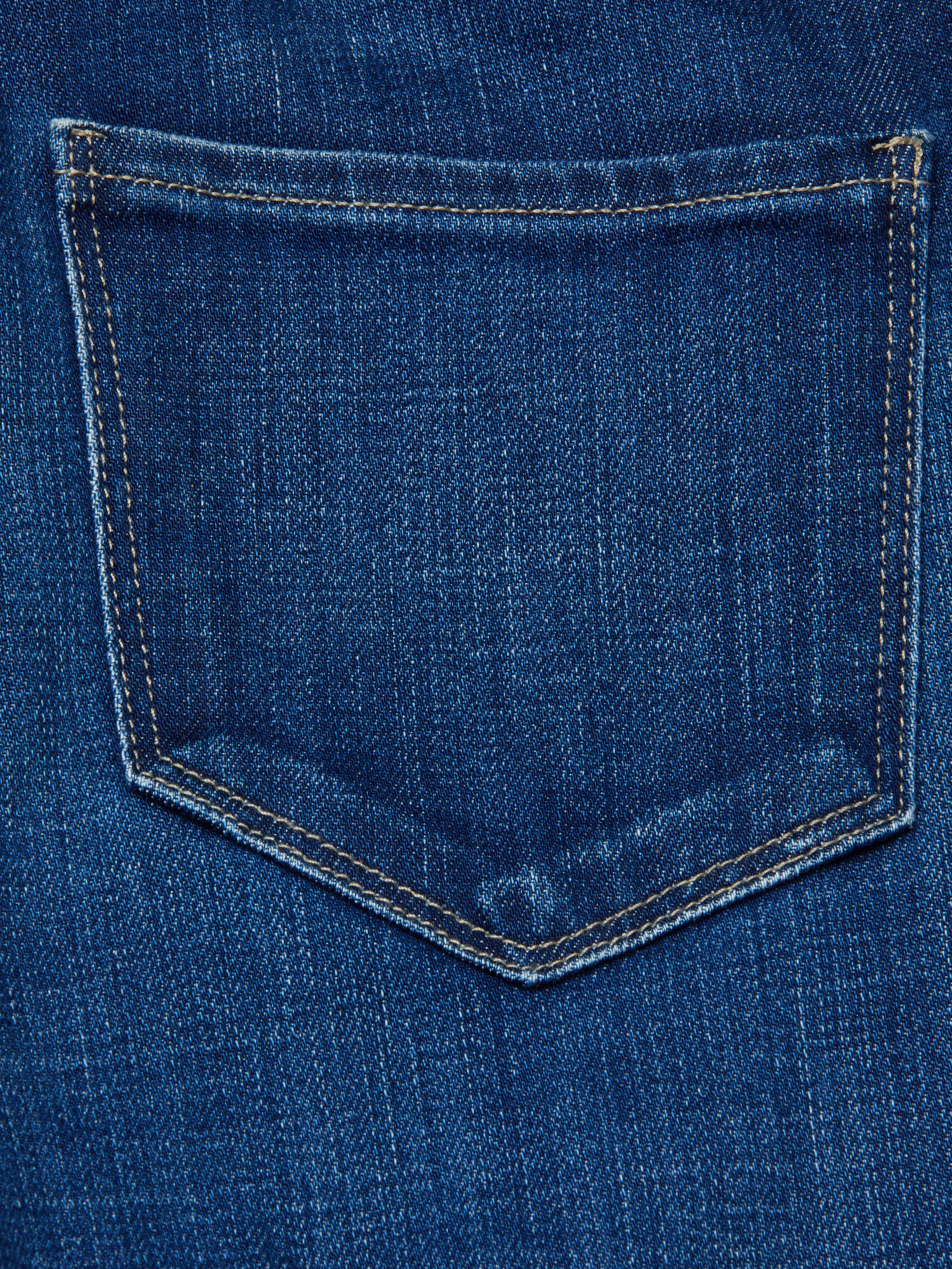 Close-up of the back pocket on the Celestia Slim-Leg Jean, featuring blue denim and visible yellow stitching around the edges.