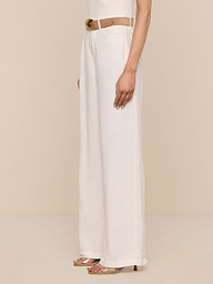 A person wearing the Amara Linen Wide-Leg Pant in cream, styled with a beige belt and open-toe heels, stands against a plain white background, shown from the waist down in a side view.