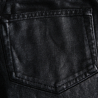 Close-up of the Mallis Coated Bow-Leg Jean pocket, highlighting the black coated denim texture and detailed stitching.