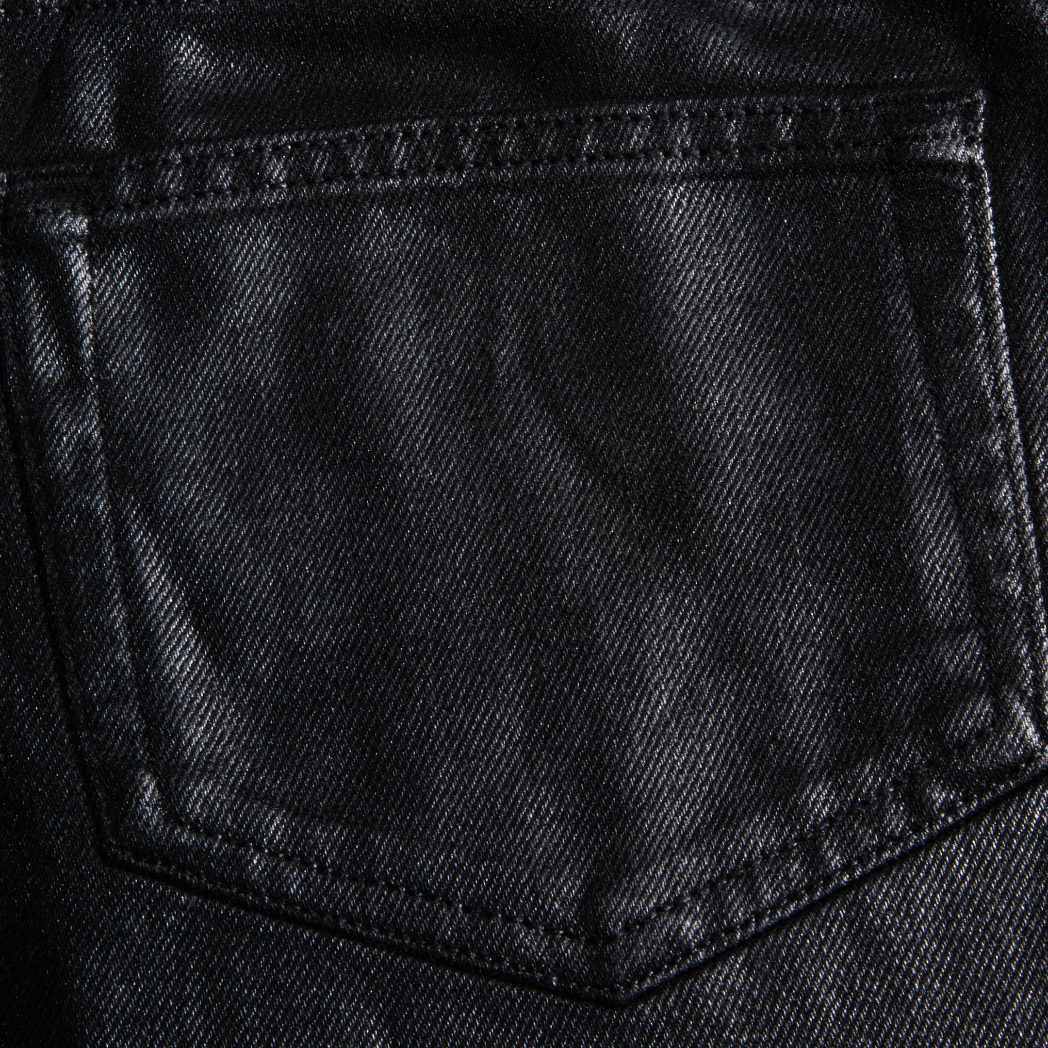 Close-up of the Mallis Coated Bow-Leg Jean pocket, highlighting the black coated denim texture and detailed stitching.