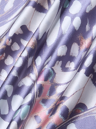 A close-up of the Ryker Silk Maxi Skirt, featuring draped silk charmeuse fabric with a colorful abstract pattern in purple, white, pink, and teal hues. The material looks smooth and shiny with soft folds and a mix of organic shapes and lines reminiscent of a butterfly wing print.