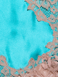 Close-up of the Tico Silk Lace Skirt in beige, showcasing its floral-patterned eyelash lace delicately draped over a smooth, bright blue satin base. The lace highlights an intricate texture and refined details.