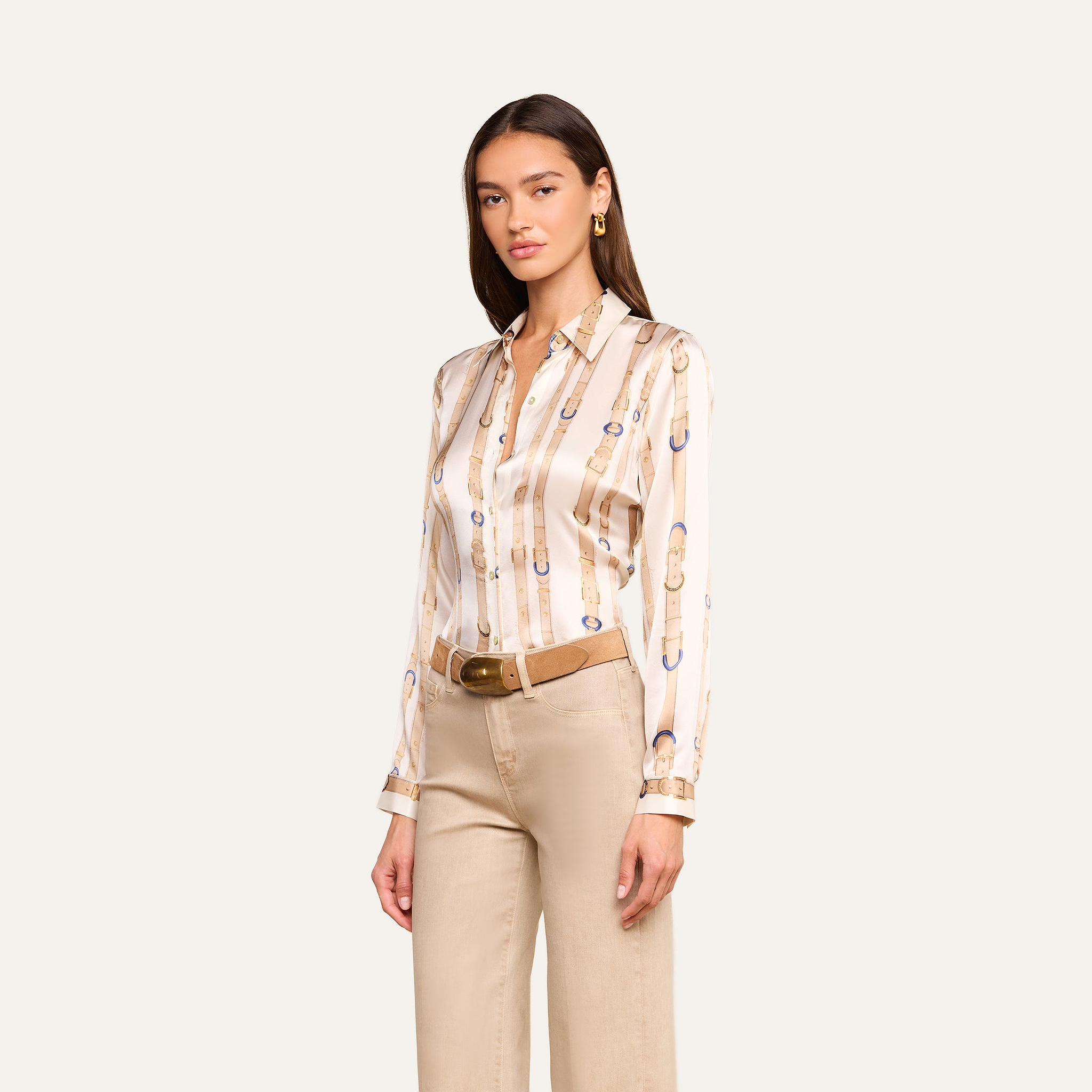 A woman wearing the Tyler Silk Blouse—a beige and gold patterned silk button-down with long sleeves—paired with tan wide-leg pants and a brown belt, standing against a plain light background.