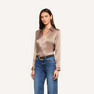 A woman wearing the Tyler Silk Blouse in cardamom brown, styled with blue jeans and a brown belt, stands against a plain light background.