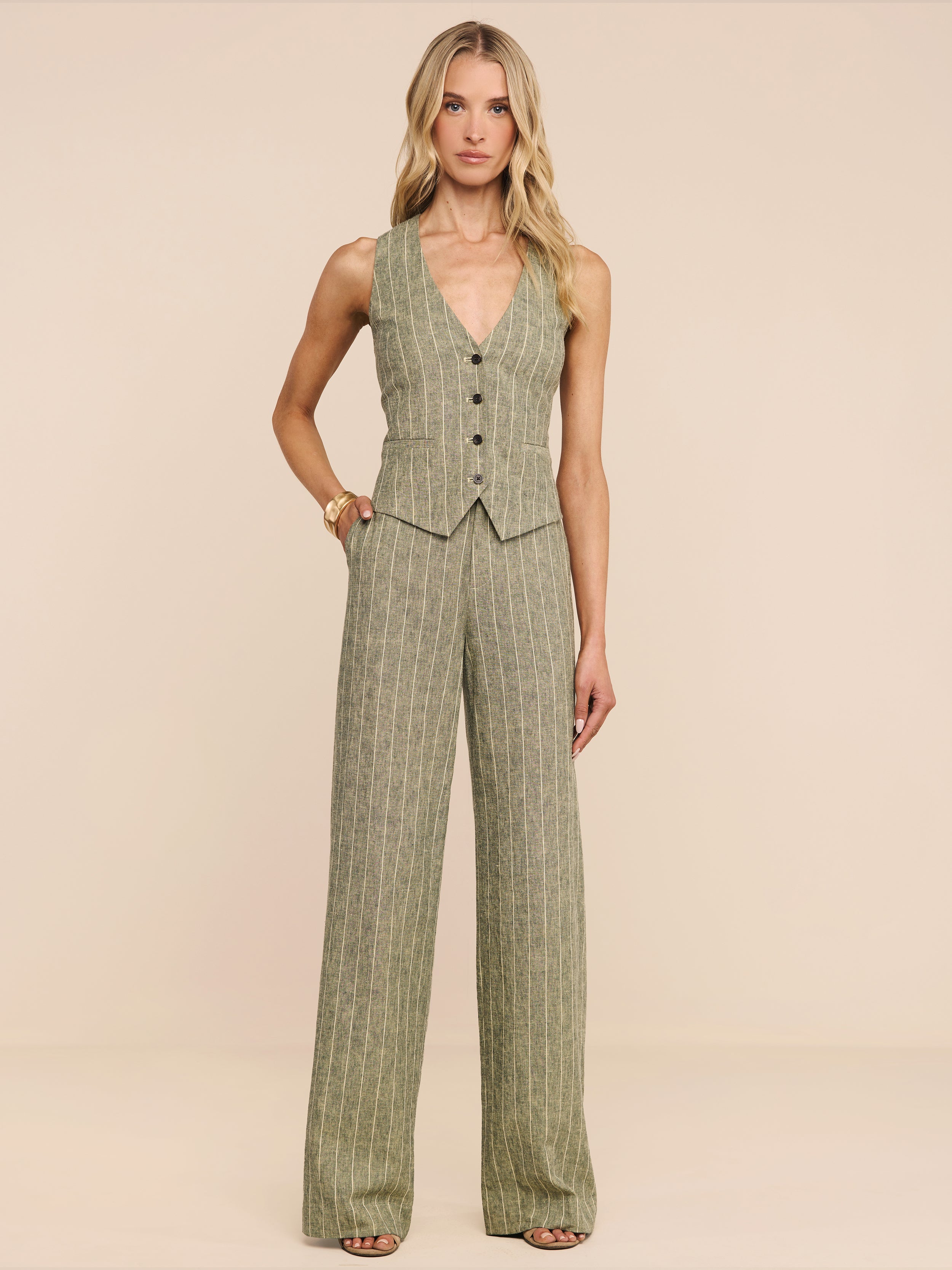 A woman stands facing forward wearing the Drina Linen-Blend Vest in olive green, paired with matching wide-leg trousers against a plain white background.