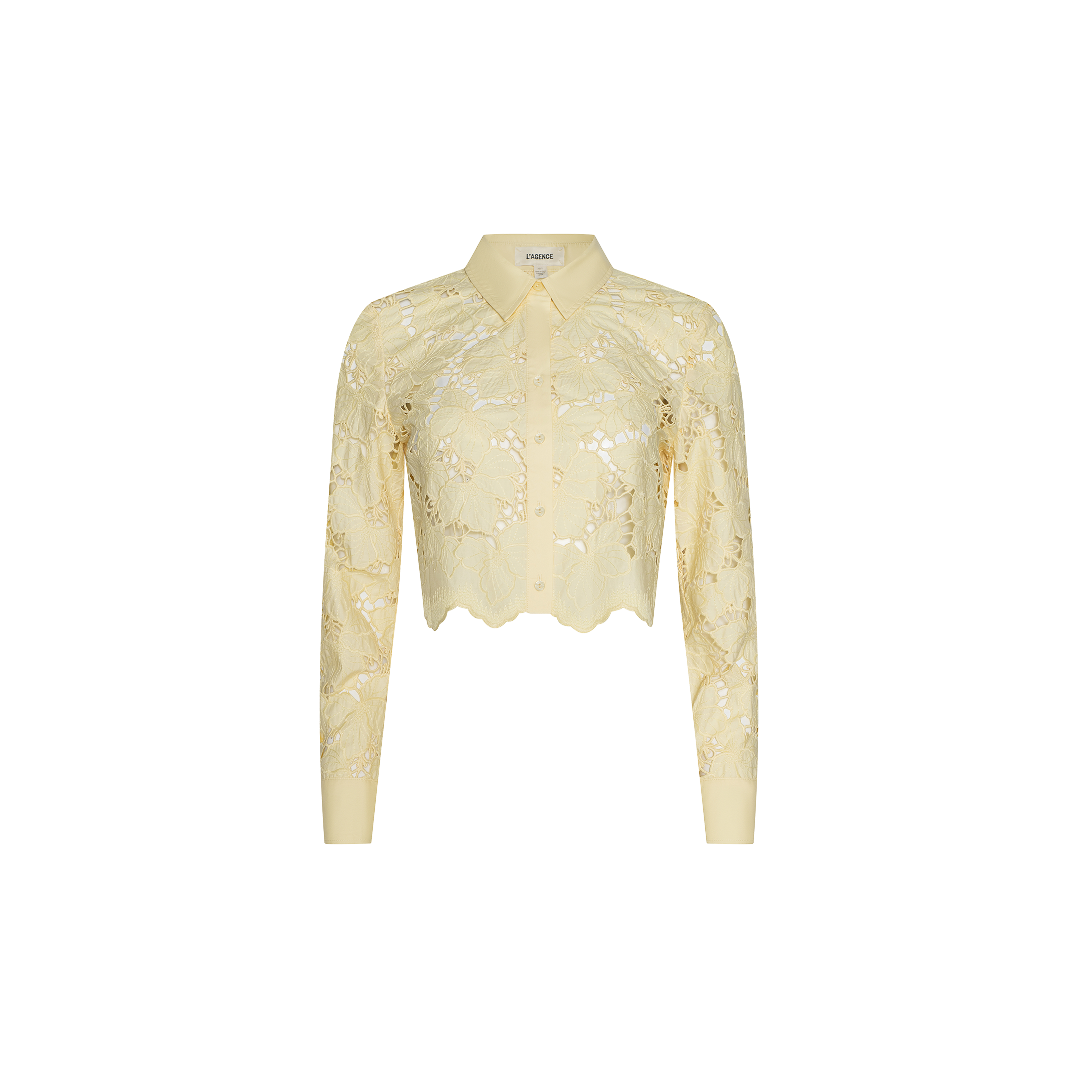 The Seychelle Cropped Eyelet Blouse is a light yellow, long-sleeve sheer poplin lace blouse featuring a collared neckline, cropped cut, and scalloped hem, displayed on a plain white background.