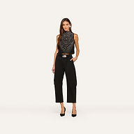 A woman with long brown hair poses against a plain background wearing the Yun Draped Crystal Tank, styled with black high-waisted pants and black heels. One hand rests in her pocket.
