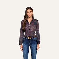 Woman with long brown hair wearing the Ellery Button-Down Shirt, tucked into blue jeans with a decorative belt, standing against a plain light background.