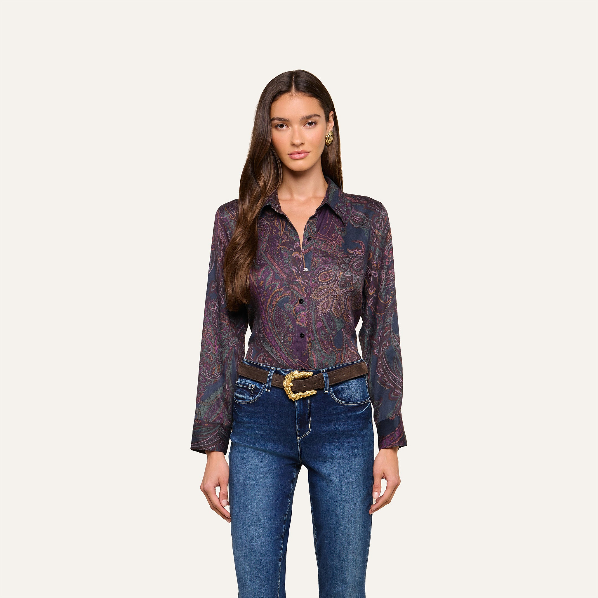 Woman with long brown hair wearing the Ellery Button-Down Shirt, tucked into blue jeans with a decorative belt, standing against a plain light background.