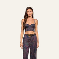 A woman with long brown hair wears the Sonya Bustier in navy paisley, paired with matching high-waisted pants and a wide brown belt, standing against a plain off-white background.