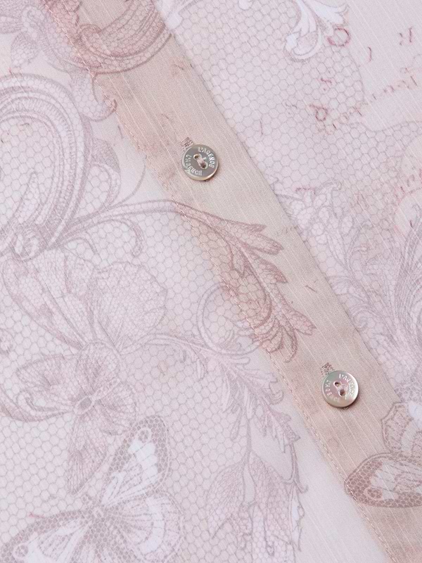 Close-up of the Laurent Blouse in sheer light pink poly chiffon, featuring intricate floral and butterfly patterns, visible stitching, and two metallic buttons along the seam.