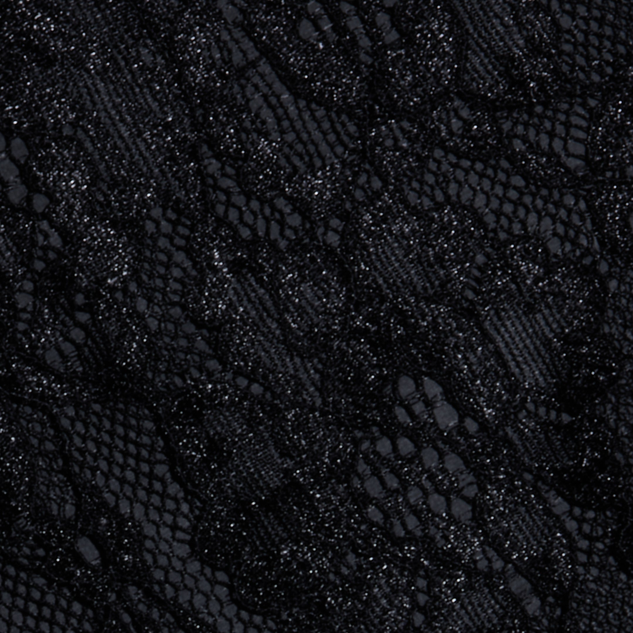 Close-up of the Henriette Cropped Lace Top in black Chantilly lace, showcasing intricate floral and mesh patterns with detailed textures and a mix of sheer and opaque areas along scalloped hems.