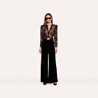 A woman wearing sunglasses, the Dorothea Velvet Lace Blouse—featuring sheer Chantilly lace with velvet seams—and high-waisted black wide-leg pants stands facing forward against a plain white background.