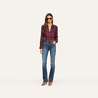 A woman wears the Suzette Shirt with sunglasses, blue jeans, a black belt, and brown shoes as she stands against a plain white background.