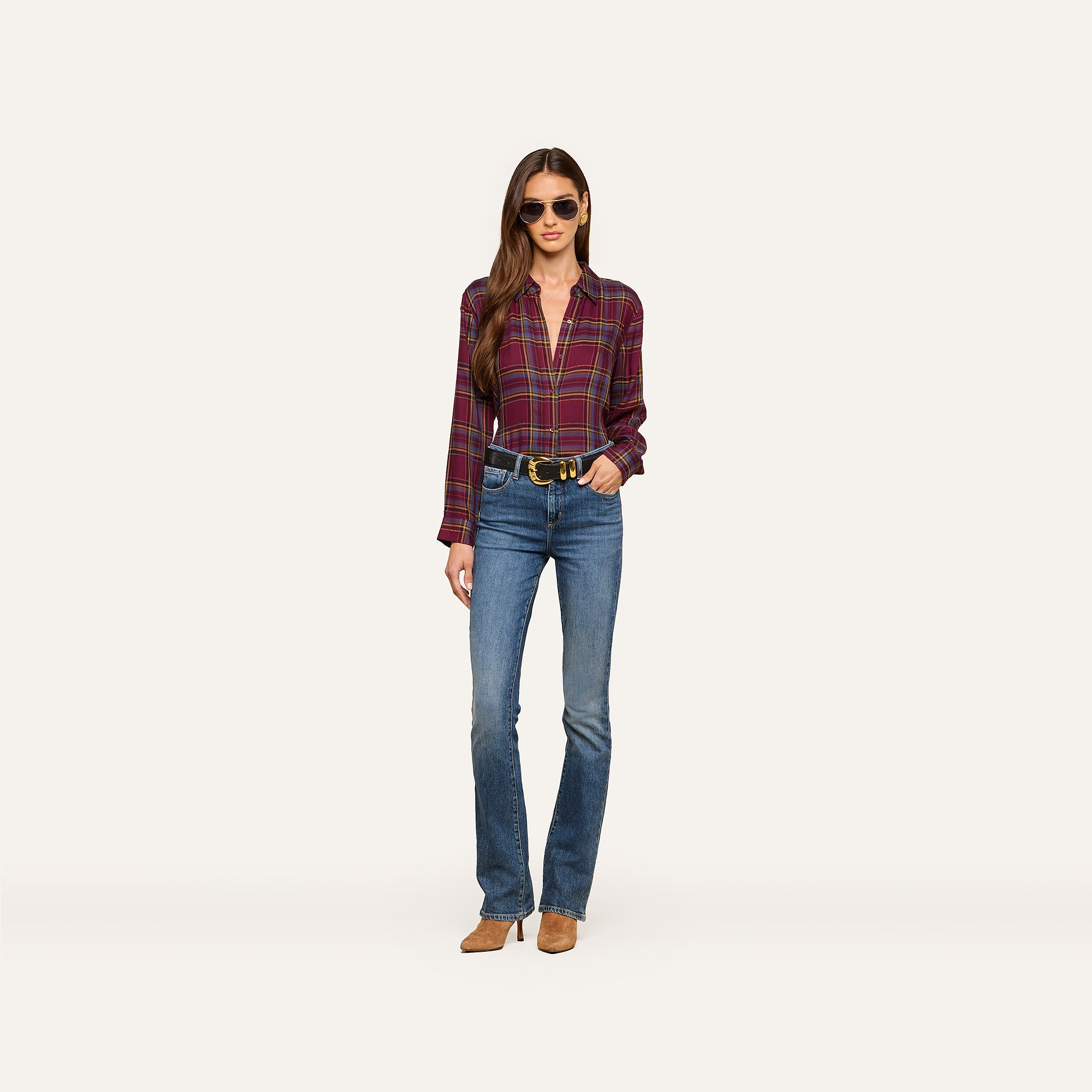 A woman wears the Suzette Shirt with sunglasses, blue jeans, a black belt, and brown shoes as she stands against a plain white background.