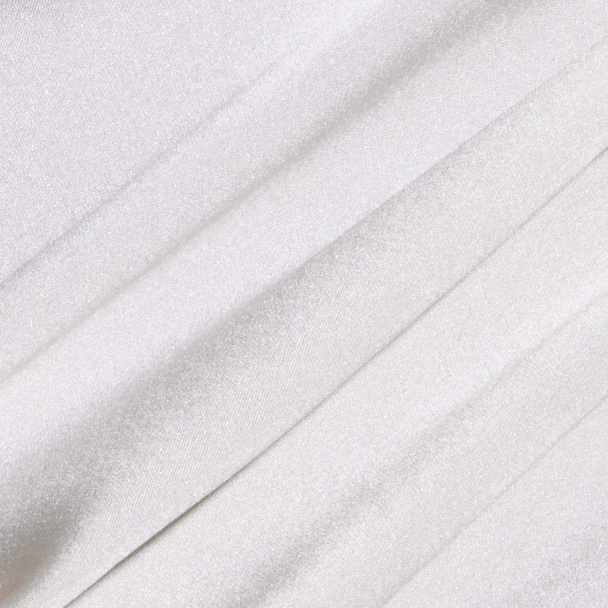 Close-up of the Soleia Lace Camisole’s white, slightly shiny silk charmeuse fabric featuring soft folds and subtle diagonal lines for a smooth and elegant texture.