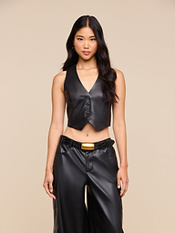 A woman with long dark hair wears the Jianna Leather Vest paired with matching black leather pants and a wide belt, standing against a plain light background. This look channels the bold energy of New York Fashion Week and highlights one of Fall 2026’s standout trends.