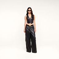A woman wearing the Jianna Leather Vest, wide-leg black leather pants, and sunglasses stands against a plain white background, channeling Fall 2026 fashion inspired by New York Fashion Week.