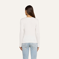 A woman with long brown hair is standing with her back to the camera, wearing the Tess Long Sleeve Tee in white and light blue jeans against a plain light background.