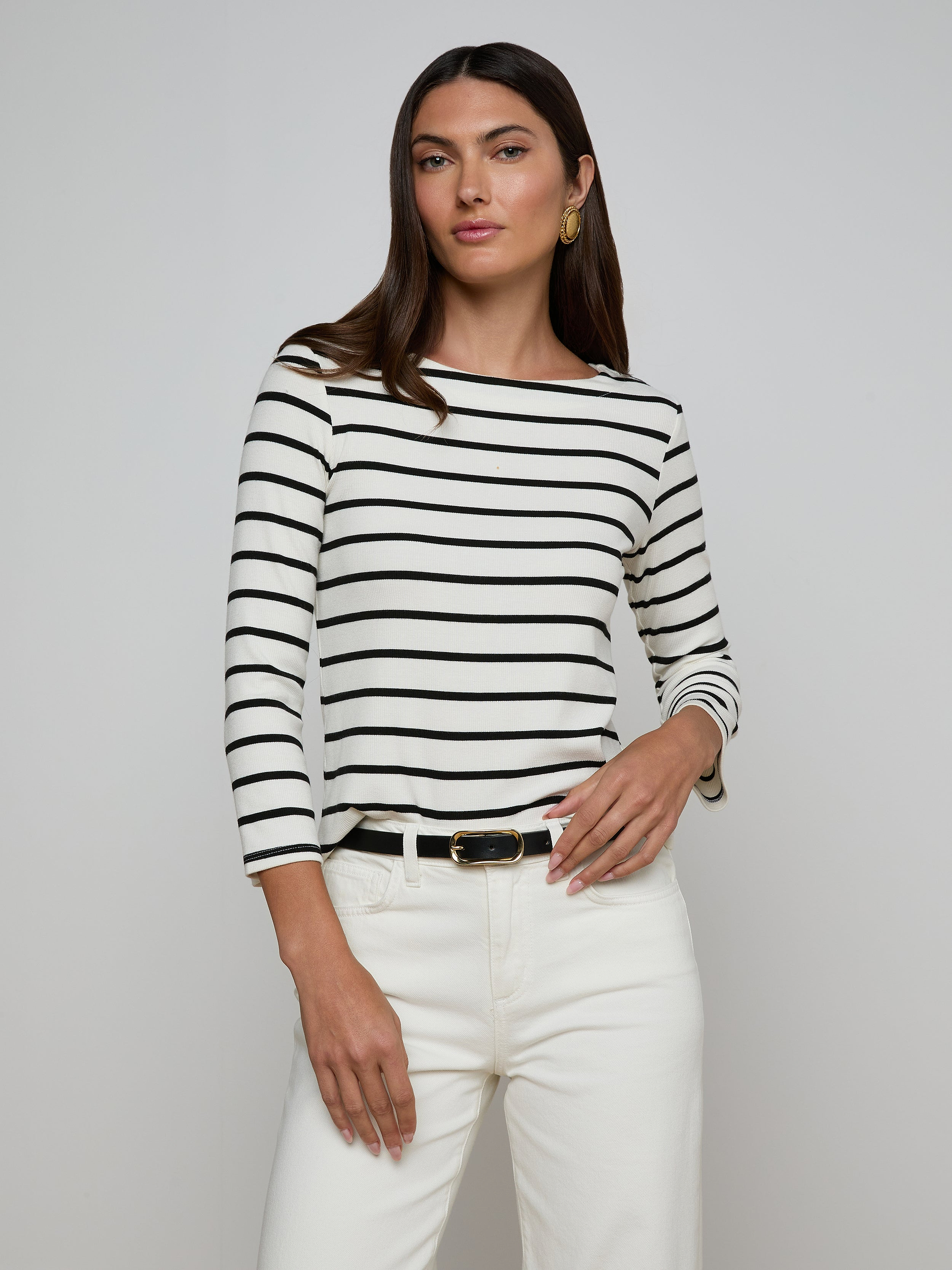 Woman wearing the Lucille Striped Boatneck Top paired with white pants and a black belt, posing against a plain light background.