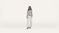 A woman wearing a black and white striped long-sleeve top, white wide-leg pants, and black sandals stands against a plain white background.