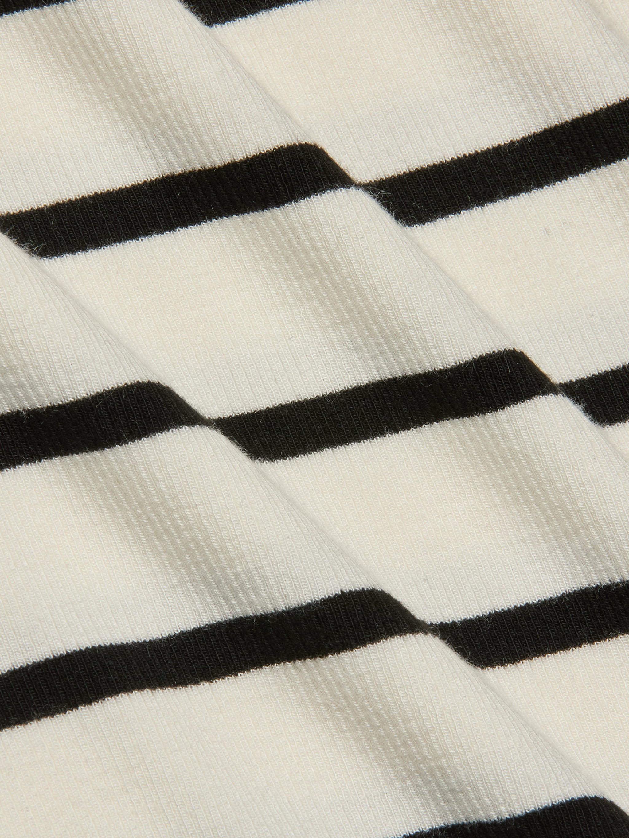 Close-up of the Lucille Striped Boatneck Top, highlighting its ribbed fabric with timeless black and white stripes arranged diagonally to showcase the texture and pattern.