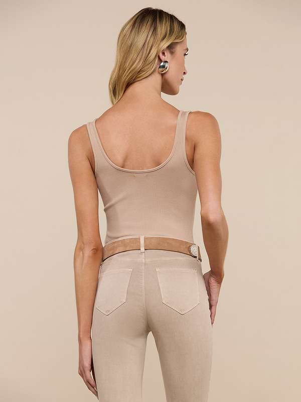 A person with long blonde hair is shown from the back, wearing the Nica Scoopneck Bodysuit in beige along with light beige jeans and a tan belt, standing against a plain light background.