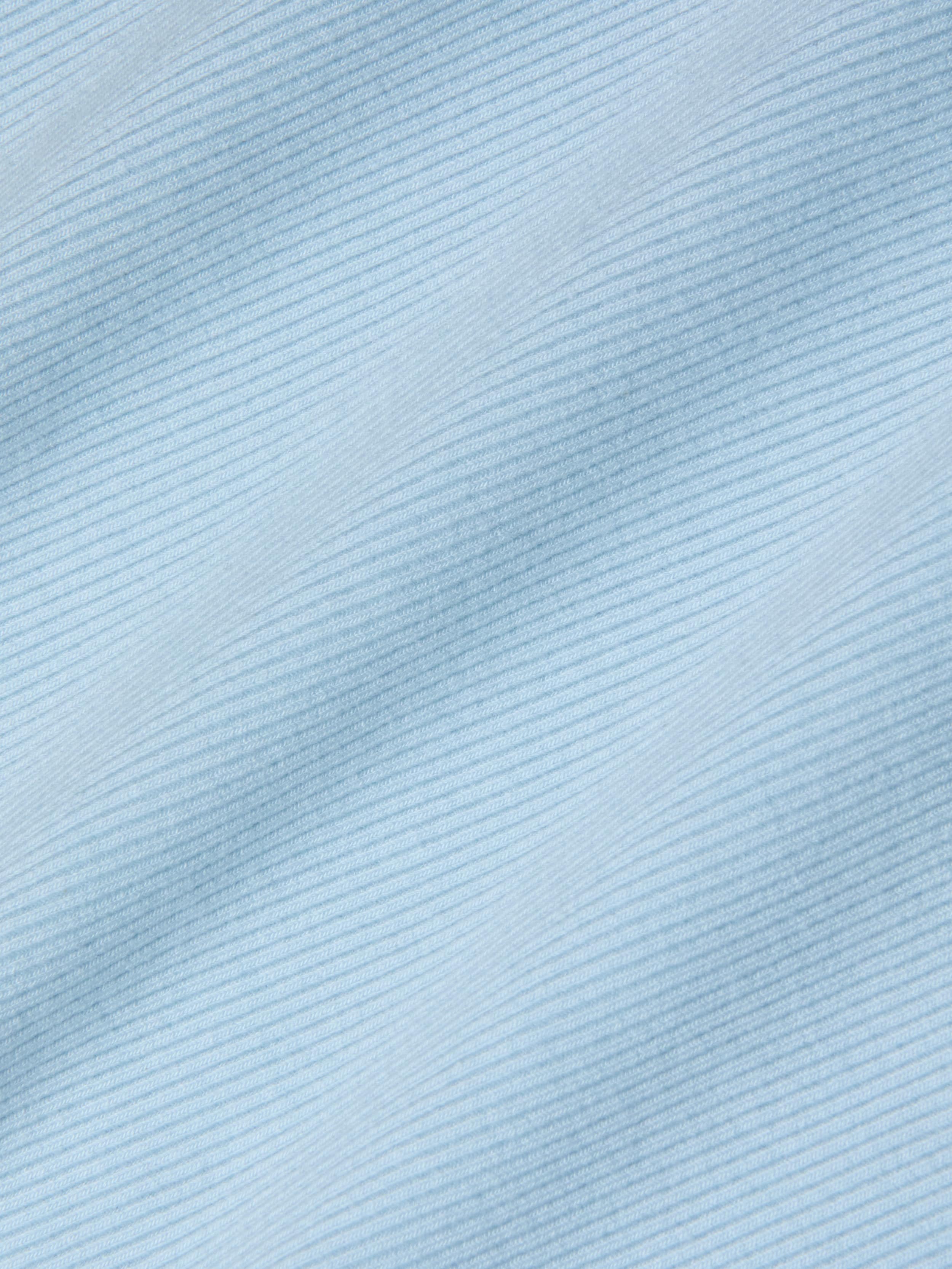 Close-up of the Nica Scoopneck Bodysuit in light blue, featuring fine, diagonal, evenly spaced lines that create a subtle striped pattern. The high recovery stretch rib enhances the soft and smooth texture, giving the fabric a gentle and calming visual effect.