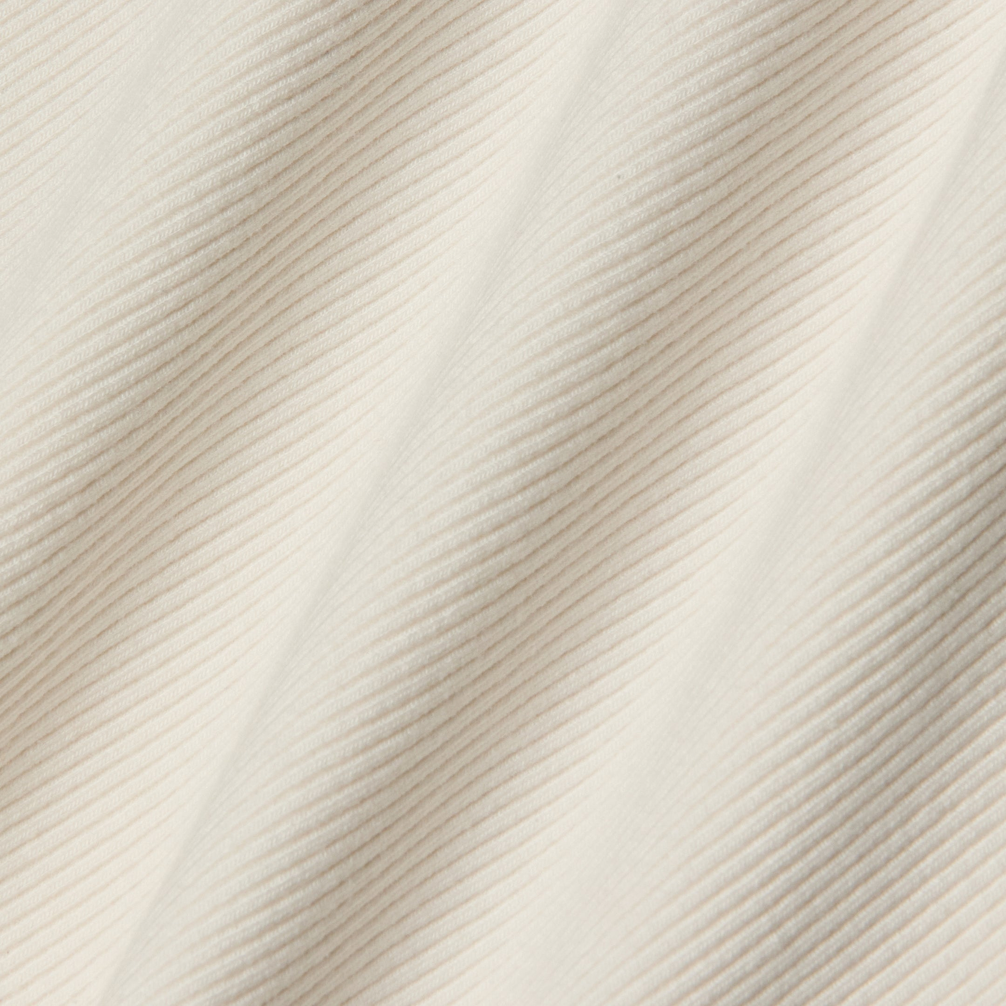 Close-up of the cream-colored corduroy fabric on the Nica Scoopneck Bodysuit, featuring visible diagonal textured lines and soft, even folds that create gentle shadows across the surface—an ideal base layer for a sculpted fit.