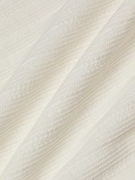Close-up of the Adira Scoopneck Tank in white ribbed knit cotton pointelle fabric, featuring diagonal lines and textured patterns, with soft folds that create a cozy appearance.