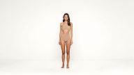 A woman stands against a plain white background, wearing nude-colored undergarments. She faces forward with her arms relaxed at her sides and her expression neutral.