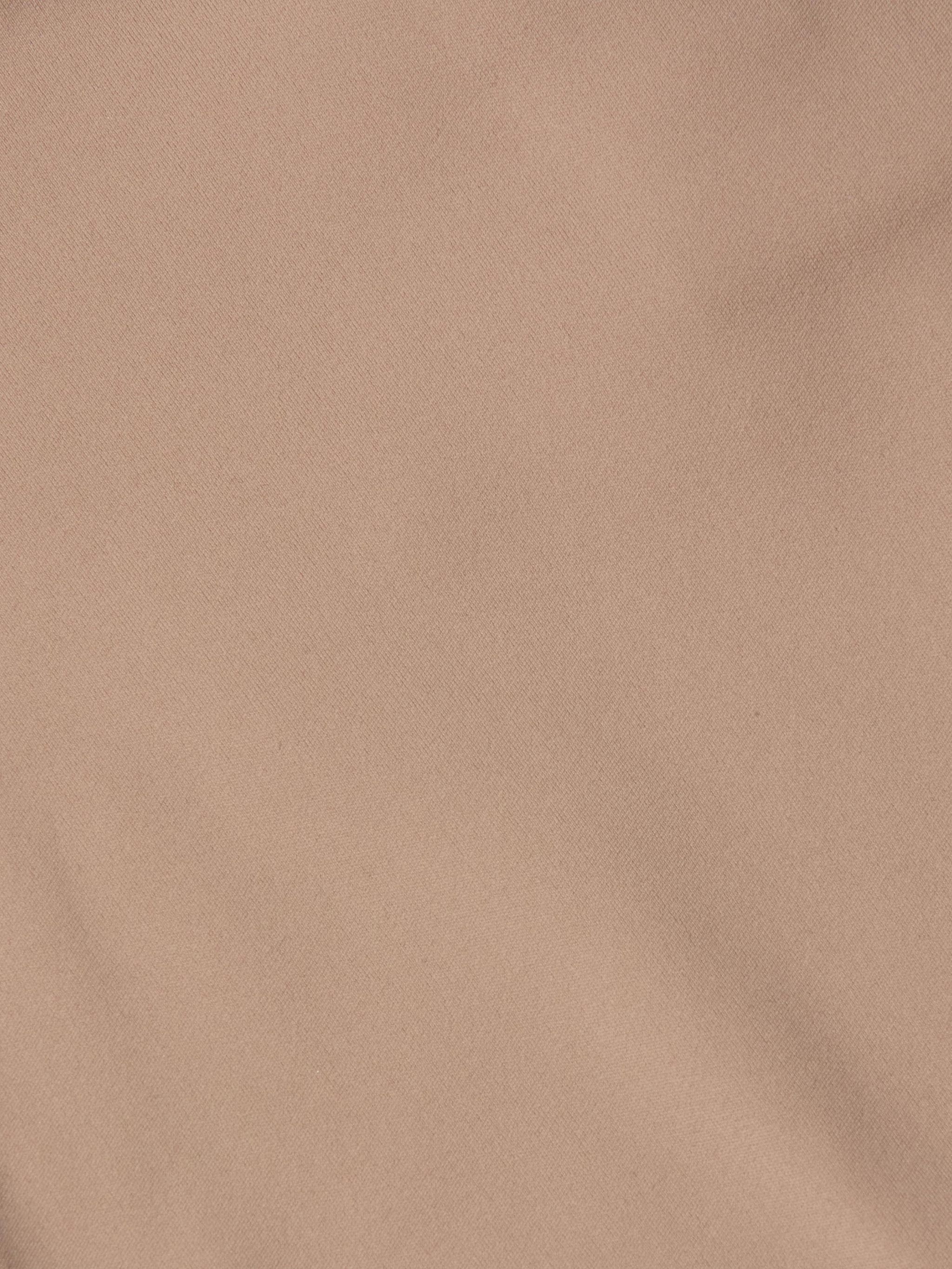 A close-up of the Mietta Knit Bandeau Top’s light brown fabric showcases subtle diagonal weave patterns and gentle creases, highlighting the stretch nylon material often used in supportive bandeau styles.