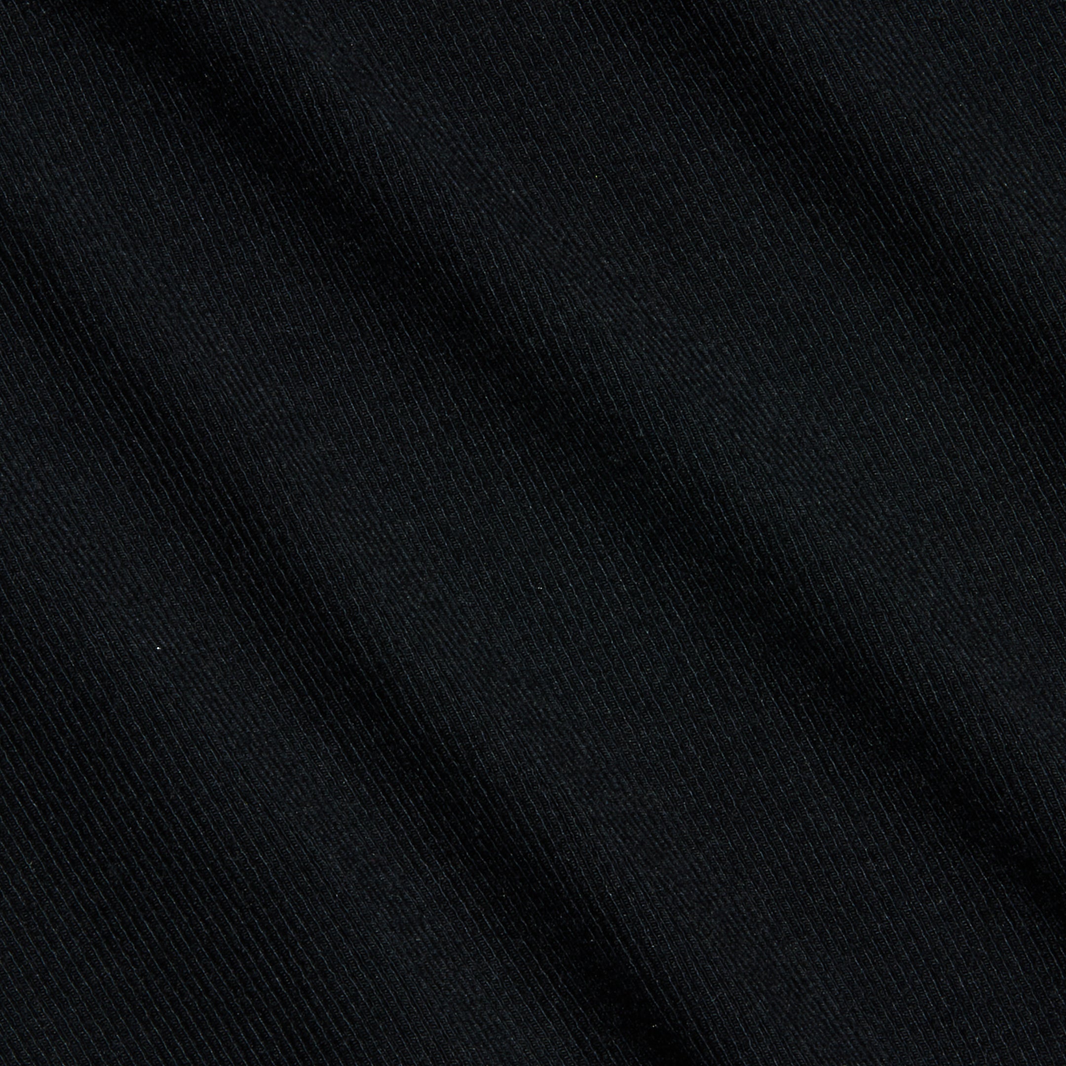 Close-up of the Wrenna Racerback Bodysuit in black, featuring fine ribbed fabric with subtle diagonal textured lines and soft folds. The lighting accentuates the material’s delicate sheen and detailed pattern.
