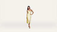A woman poses in a light yellow, sleeveless, midi-length slip dress with spaghetti straps and strappy sandals against a plain white background.