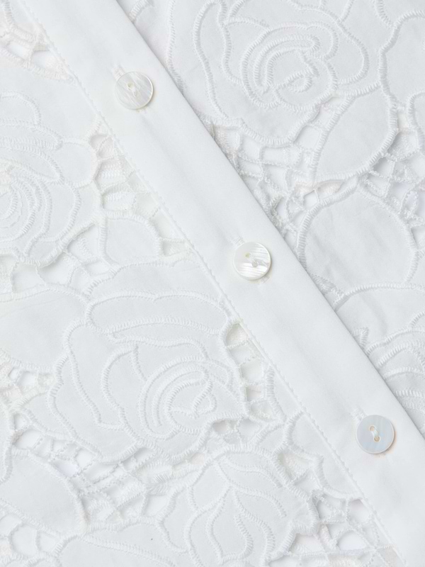 Close-up of a white lace fabric with floral patterns and three white buttons sewn along a vertical seam, reminiscent of the detailing on the May Eyelet Shirt Dress.