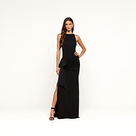 A woman stands against a plain white background, posing with one hand on her hip and wearing black heels, dressed in the sleeveless, floor-length Frost Gown featuring a high slit.