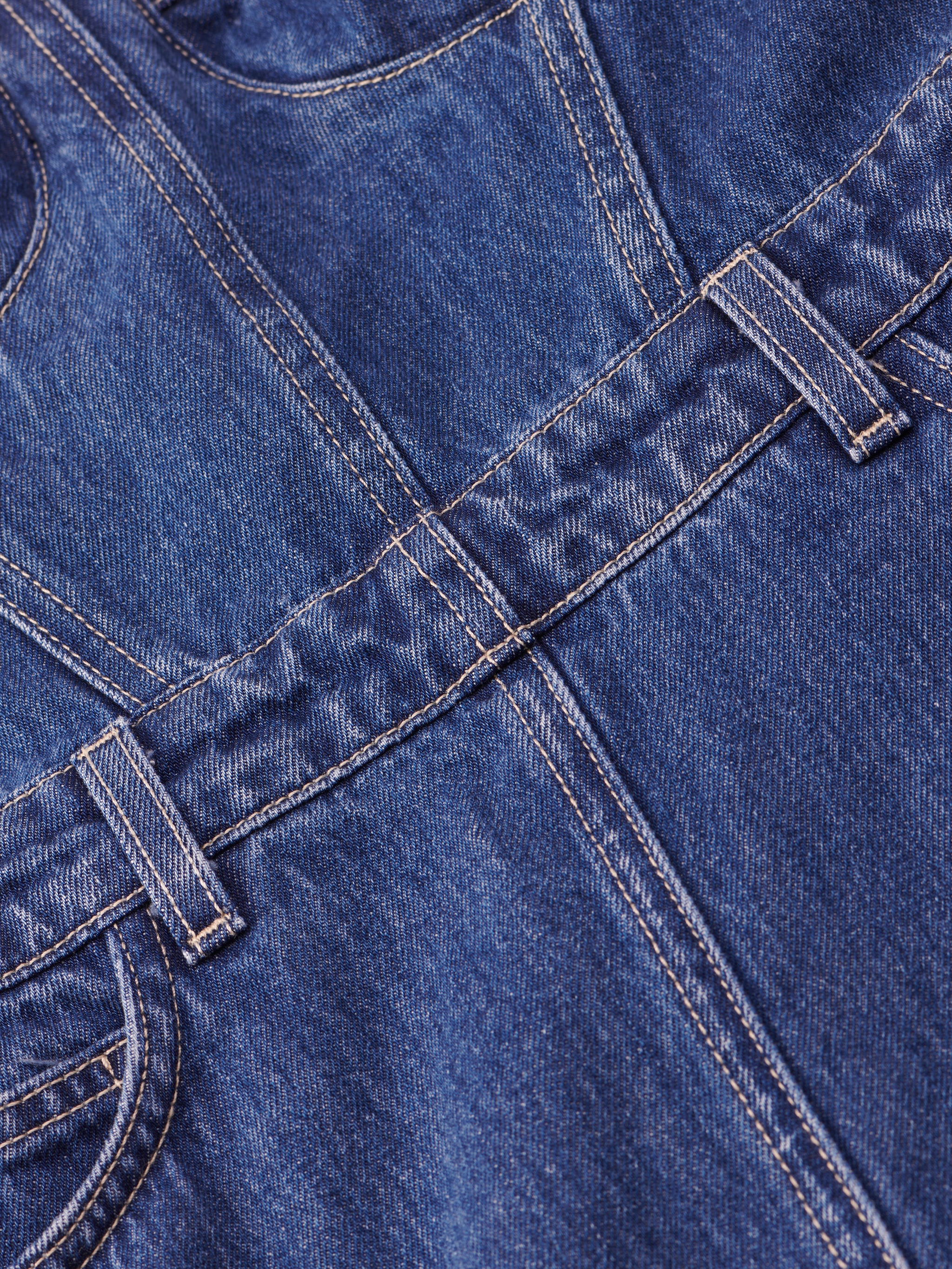 Close-up of blue denim fabric showing seams, belt loops, and stitching, featured on the Jovie Bustier Dress.