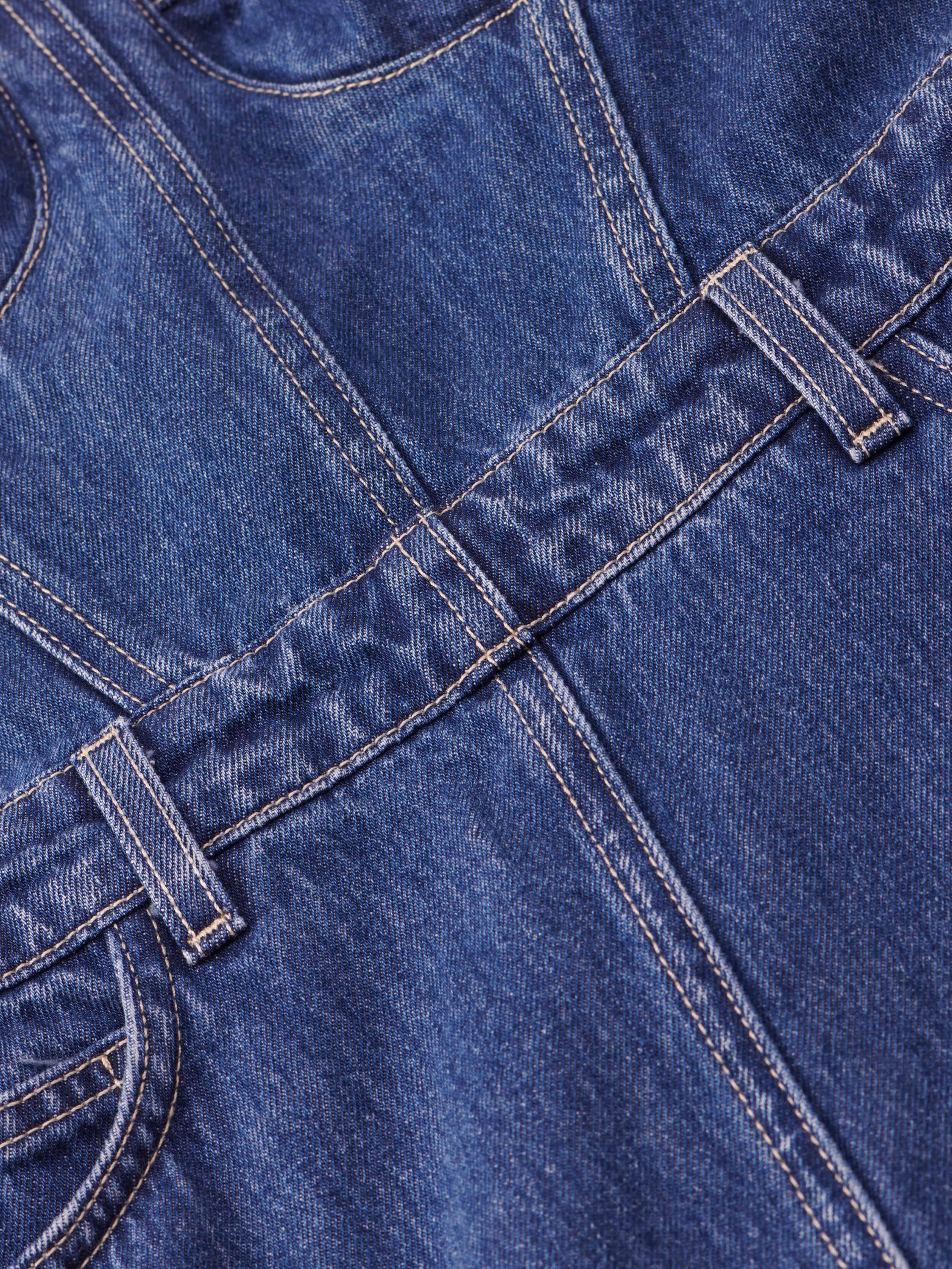 Close-up of blue denim fabric showing seams, belt loops, and stitching, featured on the Jovie Bustier Dress.