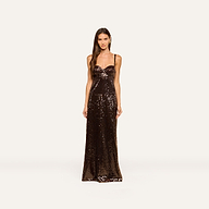 A woman stands facing forward, wearing the Sayla Sequin Gown—a floor-length, event-ready dress featuring thin straps and brown sequins—against a plain, light background.