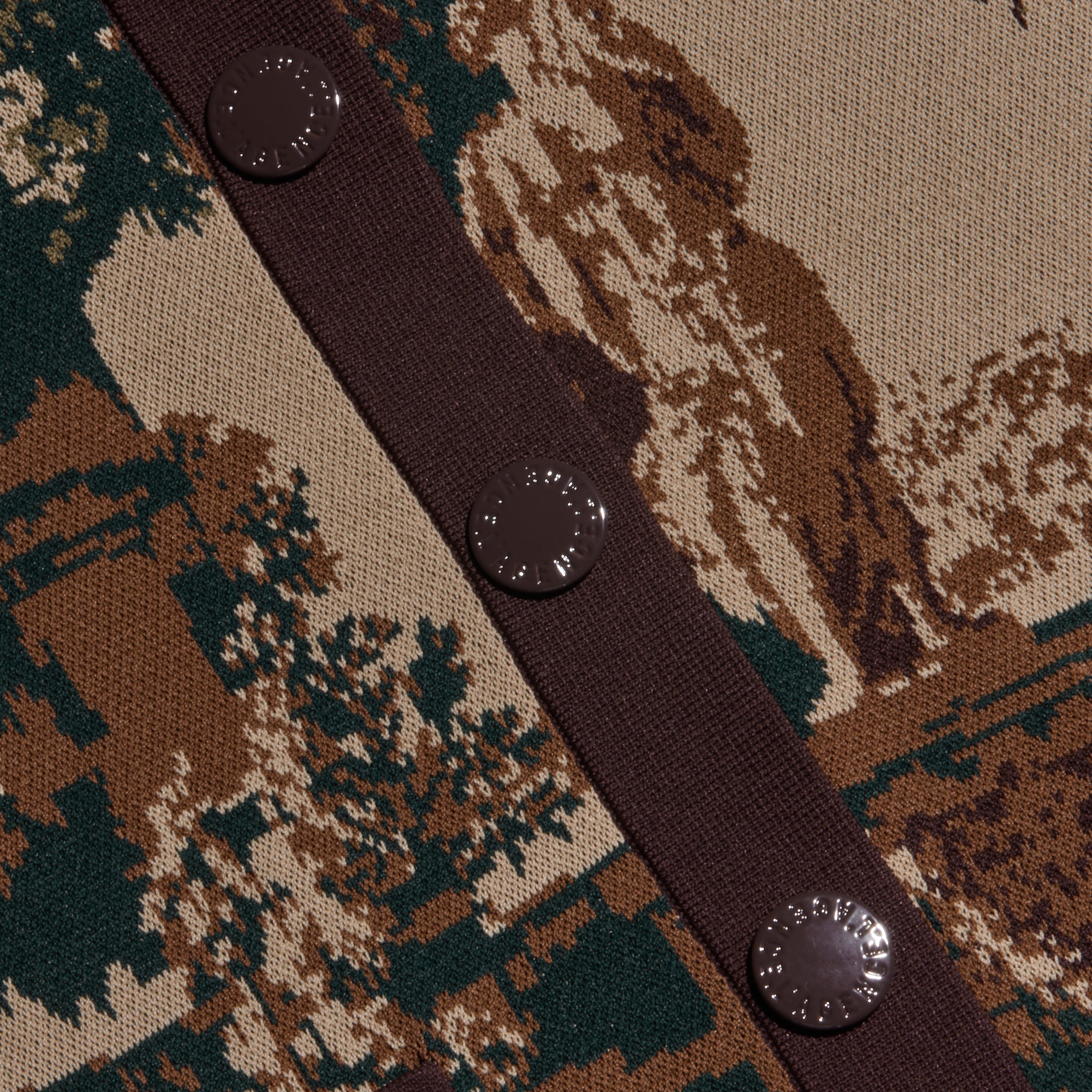 Close-up of the Osiris Jacquard Cardigan’s knit fabric, showcasing a brown, green, and beige jacquard design with four round brown buttons along a coordinating brown placket.