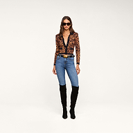 A woman wearing the Osiris Jacquard Cardigan, blue jeans, black knee-high boots, a black belt with a gold buckle, and sunglasses stands against a plain white background.