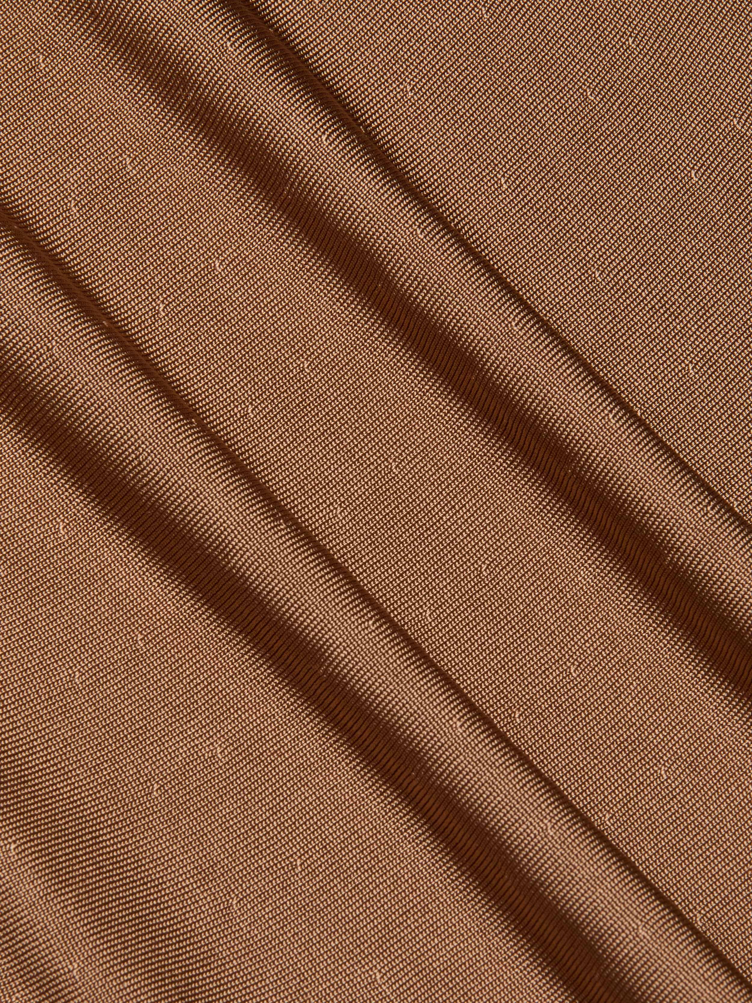 Close-up of the Lana Knit Dress in brown, showcasing textured fabric with diagonal folds and a subtle dotted pattern, evocative of elegant draping that adds depth and gentle movement.